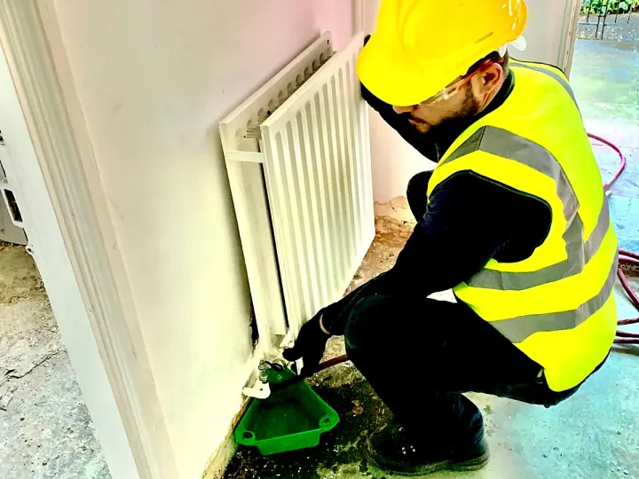 An OK Plumbing engineer draining and refitting a radiator