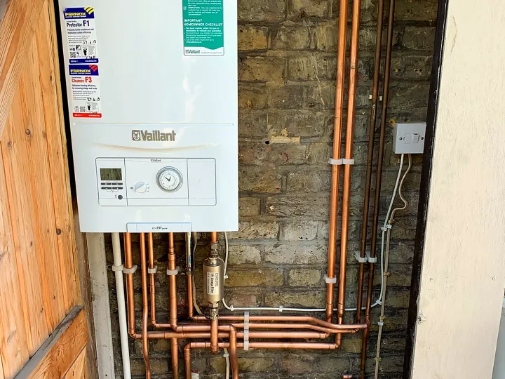 A Vaillant combi boiler with new copper pipework on a brick wall