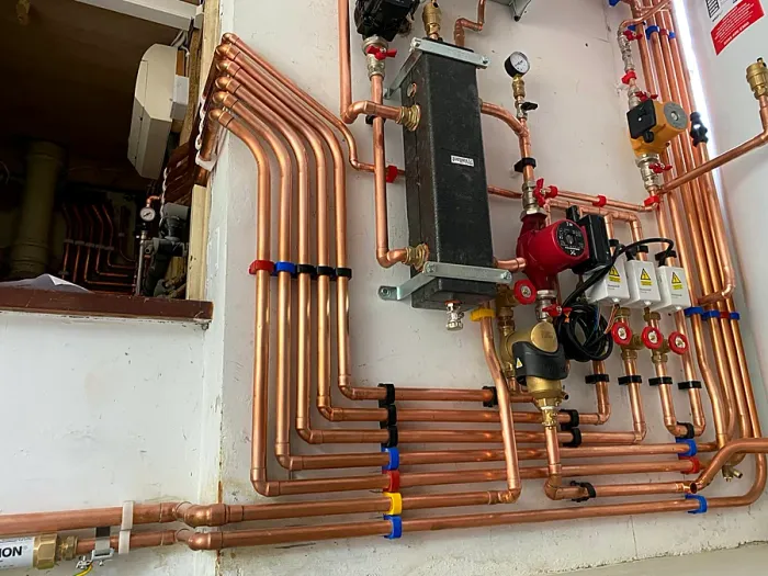Copper pipework, zone valves and a pump on a finished heating manifold