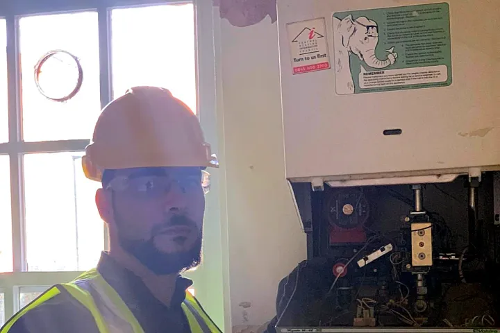 An engineer checking the controls inside a gas boiler with the case off