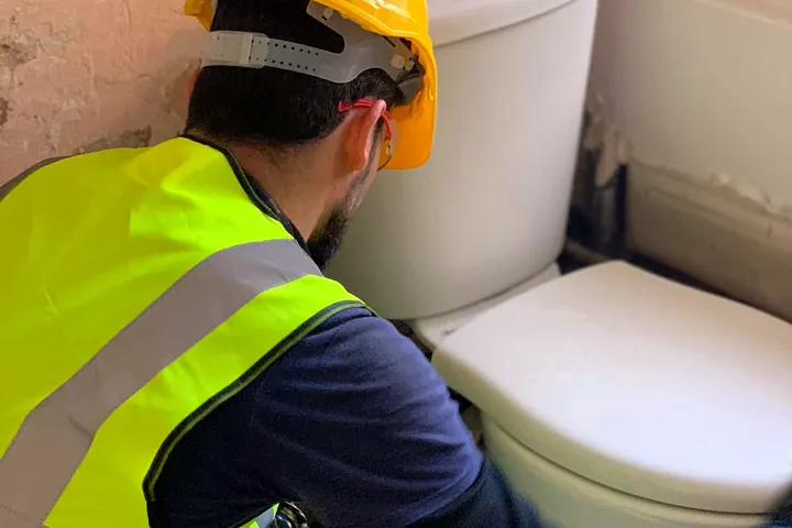 An engineer fitting a close-coupled toilet during a refit